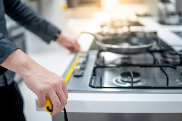 Male hand interior designer using tape measure on gas stove on modern countertop in kitchen showroom. Shopping appliance for domestic kitchen. Home improvement concept