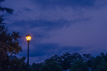 Single lone street light lamp post at night shining in the dark in the evening