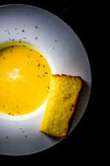 Homemade cream of pumpkin soup served with dash of cream and garlic bread