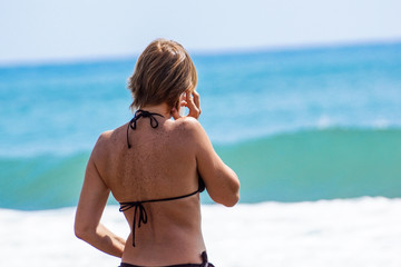 Landscape with the beautiful happy girl, talking on phone on a sea coast