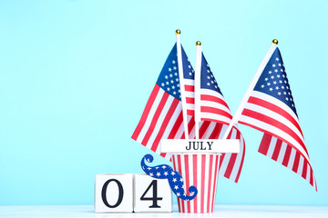 Independence Day on calendar and paper cup with american flags on blue background