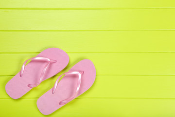 Pair of flip flops on green wooden table
