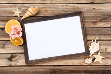 Wooden blank frame with seashells and orange fruits on brown table