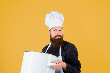 Cook man in apron holds saucepan in kitchen. Cookware, dinnerware, kitchenware. Cooking pot, saucepan, casserole. Cooking, culinary, food, profession and people concept - male chef cook holds big pot.