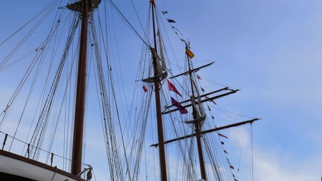 View of a beautiful old yacht with masts. On the masts waving flags against the sky