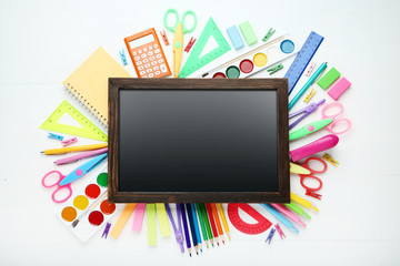 Black frame with school supplies on white wooden table