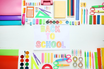 Inscriptions Back To School with school supplies on wooden table