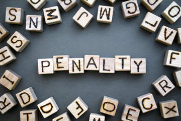 the word penalty wooden cubes with burnt letters, penalty for tax evasion, gray background top view, scattered cubes around random letters