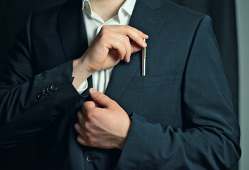 businessman in a suit taking or putting a pen from the breast pocket of his jacket