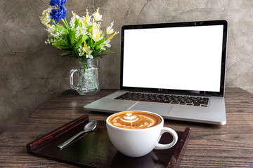 Latte art coffee with blank screen of laptop computer on wooden table