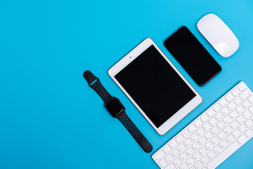 Smart phone, Smart watch, tablet, mouse and keyboard on sky blue background, Flat lay