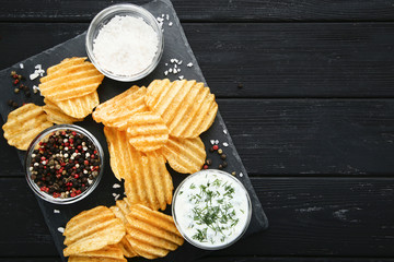 Potato chips with sauce and peppers on wooden table