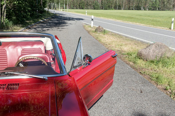 Old red Ford Mustang Cabriolet is parked at the street