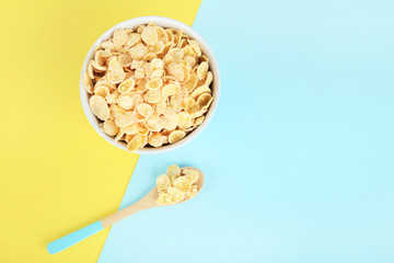 Corn flakes in bowl with spoon on colorful background