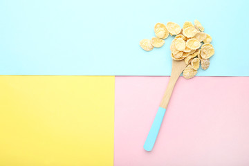 Corn flakes in wooden spoon on colorful background