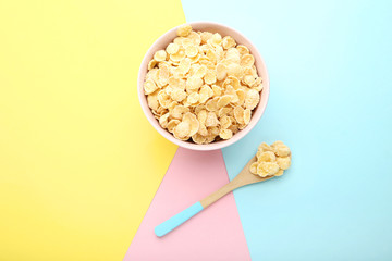 Corn flakes in bowl with spoon on colorful background