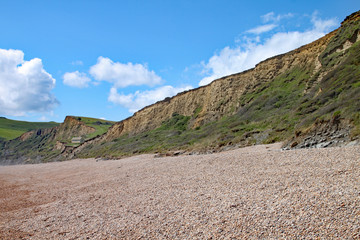 The shingle beach at Eype in Dorset on a sunny day, The sandstone cliffs of the Jurassic coast can be seen in the background