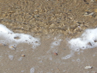 Angespülter, weißer Schaum am Strand als Hintergrund mit Raum für Text