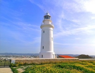 Beautiful landscaape with white lighthouse, blue sky and green grass
