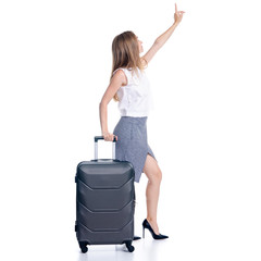Woman in high heels shoes and skirt with travel suitcase standing showing pointing smiling on white...