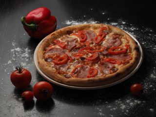Pizza with sausage, tomatoes and cheese on a plate