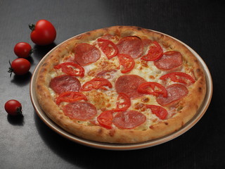 Pizza with salami, tomatoes and cheese on a plate