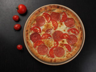 Pizza with salami, tomatoes and cheese on a plate