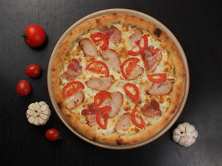 Pizza with ham, chicken, tomatoes and cheese on a plate
