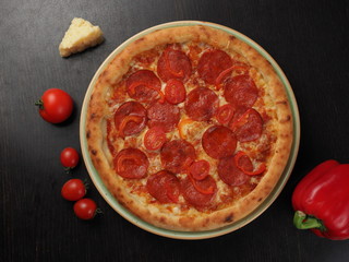 Pizza with salami, tomatoes and cheese on a plate