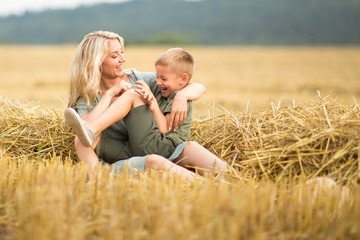 Family photo: mom blonde with long hair and son playing in the field. The family in the village. Family value