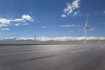 empty asphalt road with nobody and wind turbines for clean energy.