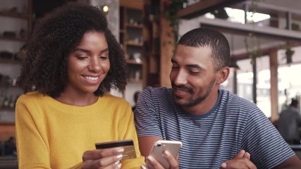 Couple in a cafe shopping online with credit card - Powered by Adobe