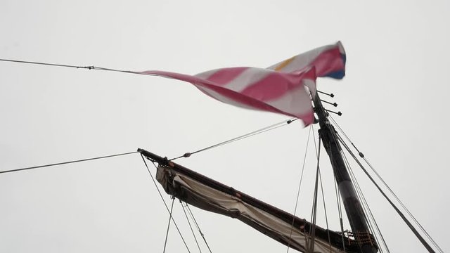 View of a beautiful old yacht with masts. On the masts waving flags against the sky. Slow motion