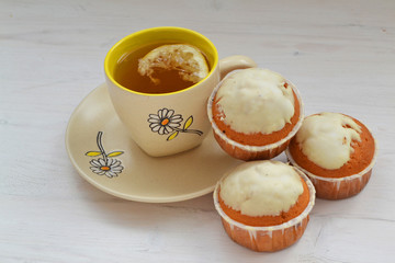 Sweet cupcakes on shabby wooden table with cup of tea