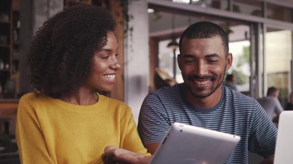 Young couple in coffee shop using digital tablet - Powered by Adobe