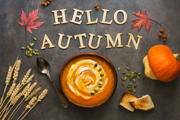 Pumpkin cream soup on an autumn background, leaves of maple, wheat ears, seeds, toast. The concept of autumn food m holiday.View from above.