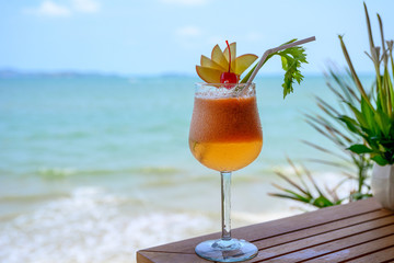 Apple mocktail with cherry in wine glass in tropical sea