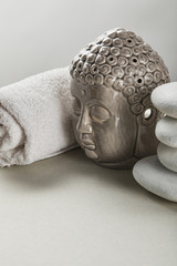 cotton towel, stones, Buddha figurine on white table isolated on grey