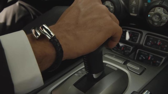 Businessman uses transmission. Man hand on automatic transmission car lever. Driver controls auto and switch gears. Close up of gear shift in car. Gearbox auto or manual transmission. Car dashboard.