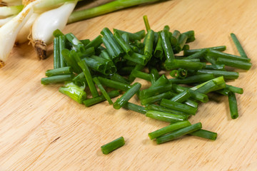 chopped of fresh scallion or spring onions on wooden board