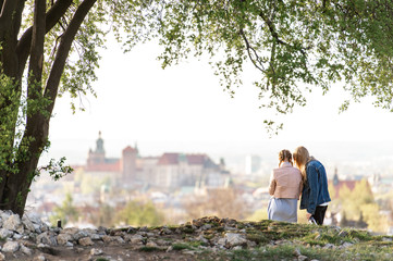 Female couple from behind on Krakus mound with a view at Wawel castle on background.