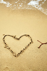 Heart shaped symbol on a sandy beach in summertime.