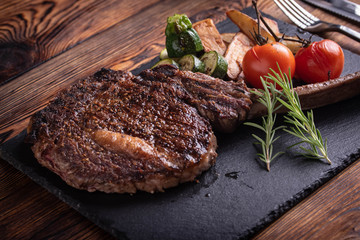 grilled tomahawk ribeye steak on black stone plate