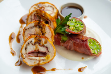 close up of stuffed pork cutlet with ham, cheese and vegetable isolated on a white plate