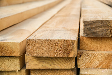 Stacked lumber. Folded wood.Closeup wooden boards.The surface of the end of the board.Lots of planks stacked on top of each other in the warehouse.Lumber for use in construction.