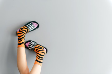 Beautiful female legs in striped trendy orange socks wearing fashionable rubber slippers with...