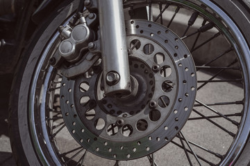 Motorcycle wheel with disk brakes system and metal spokes. Close up detailed photo of motorbike forks and tire. Different parts of two-wheeled vehicle. Transportation. Modern driving technologies.