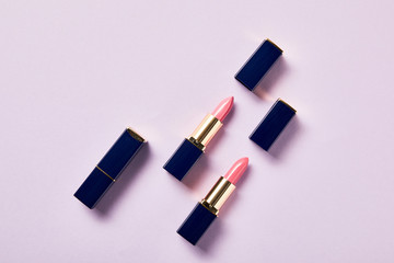 Fototapeta na wymiar top view of various pink shades of lipsticks in tubes on violet