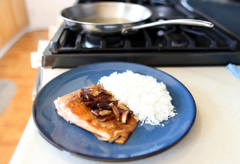 Plate of steelhead trout with chopped garlic and rice.