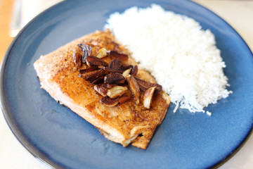 Plate of steelhead trout with chopped garlic and rice.